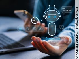 Person am Laptop, die in einer Hand ein Smartphone hält, über der anderen Hand ist die Grafik eines KI Roboters zu sehen